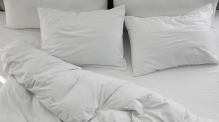 A bed with white pillows and a comforter.