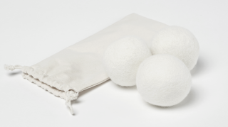Three white wool balls next to a bag.