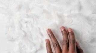 A hand touching a white surface.
