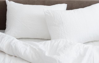 A white bed with two pillows a comforter.