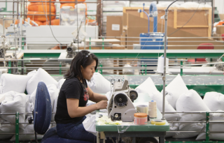 A woman sowing pillows on a sowing machine.