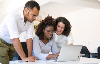 Three people are gathered around a laptop, engaged in a discussion about innovation and development.
