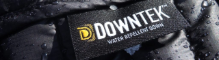 Close-up of a black down jacket with water droplets and snow on it, showing a DownTek Water Repellent Down label.